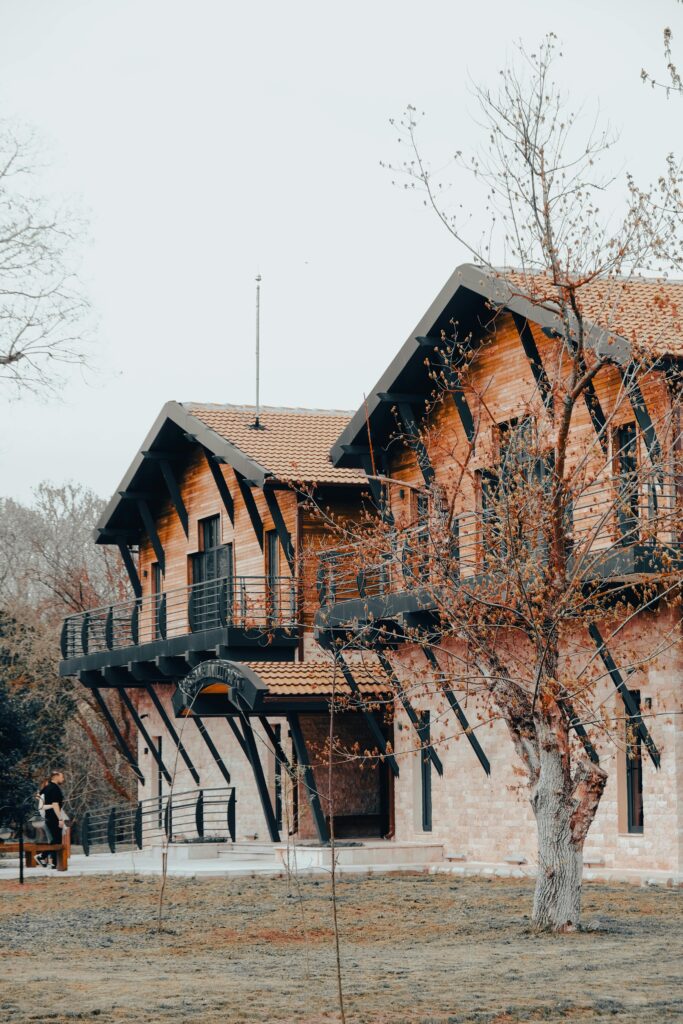 Charming rustic wooden house with balcony set in serene autumn landscape.